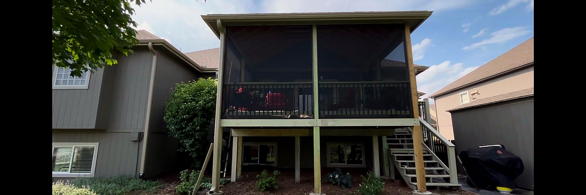 Finished screened-in porch on the rear of a two-story house.