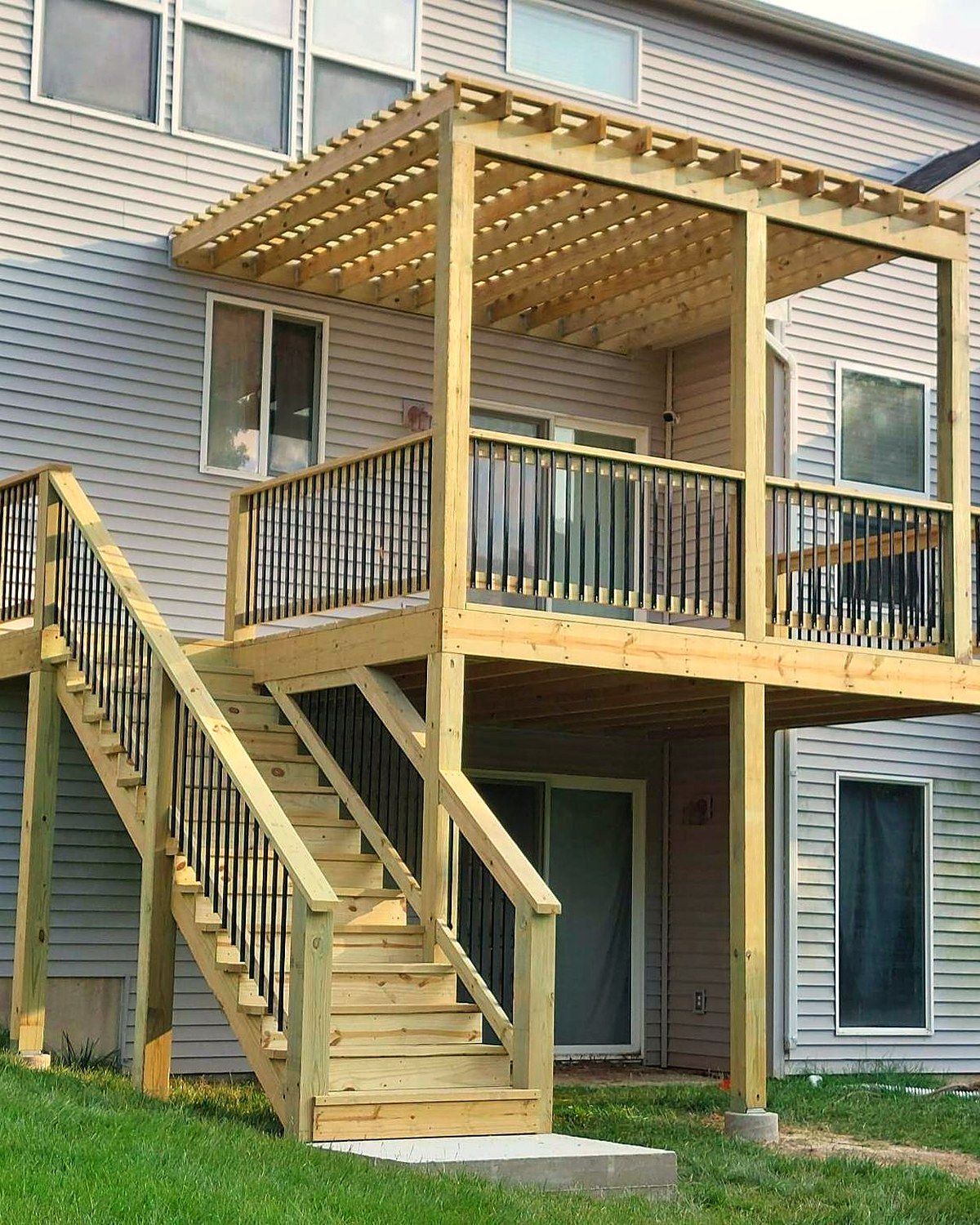 A two-storey deck with a timber pergola and stair run at the back of a home.