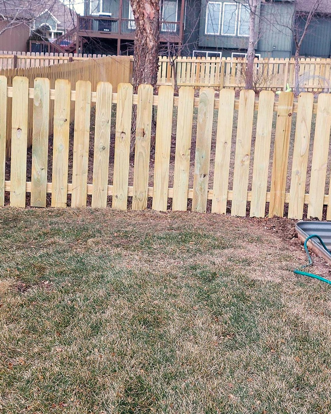 New cedar picket fence with the posts set along a property line.