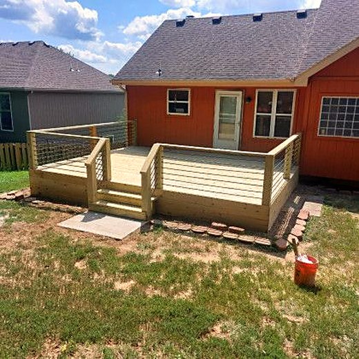 Low deck with a bench-height rail behind a red brick ranch home.