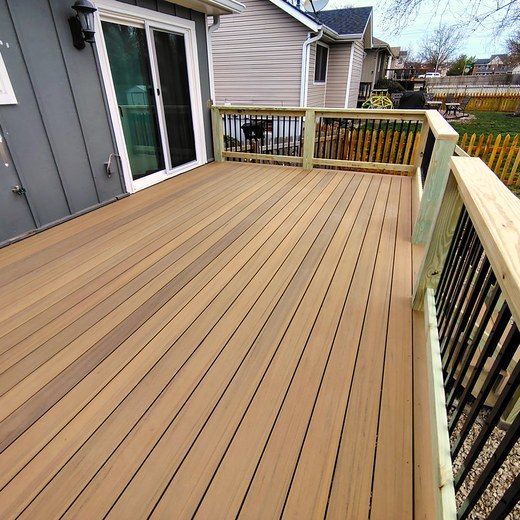 Composite deck boards running toward a black metal railing.