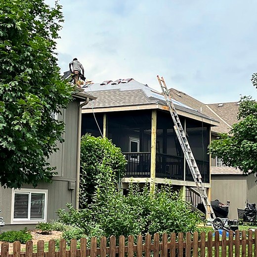Crew member on the roof of a screened porch under construction.