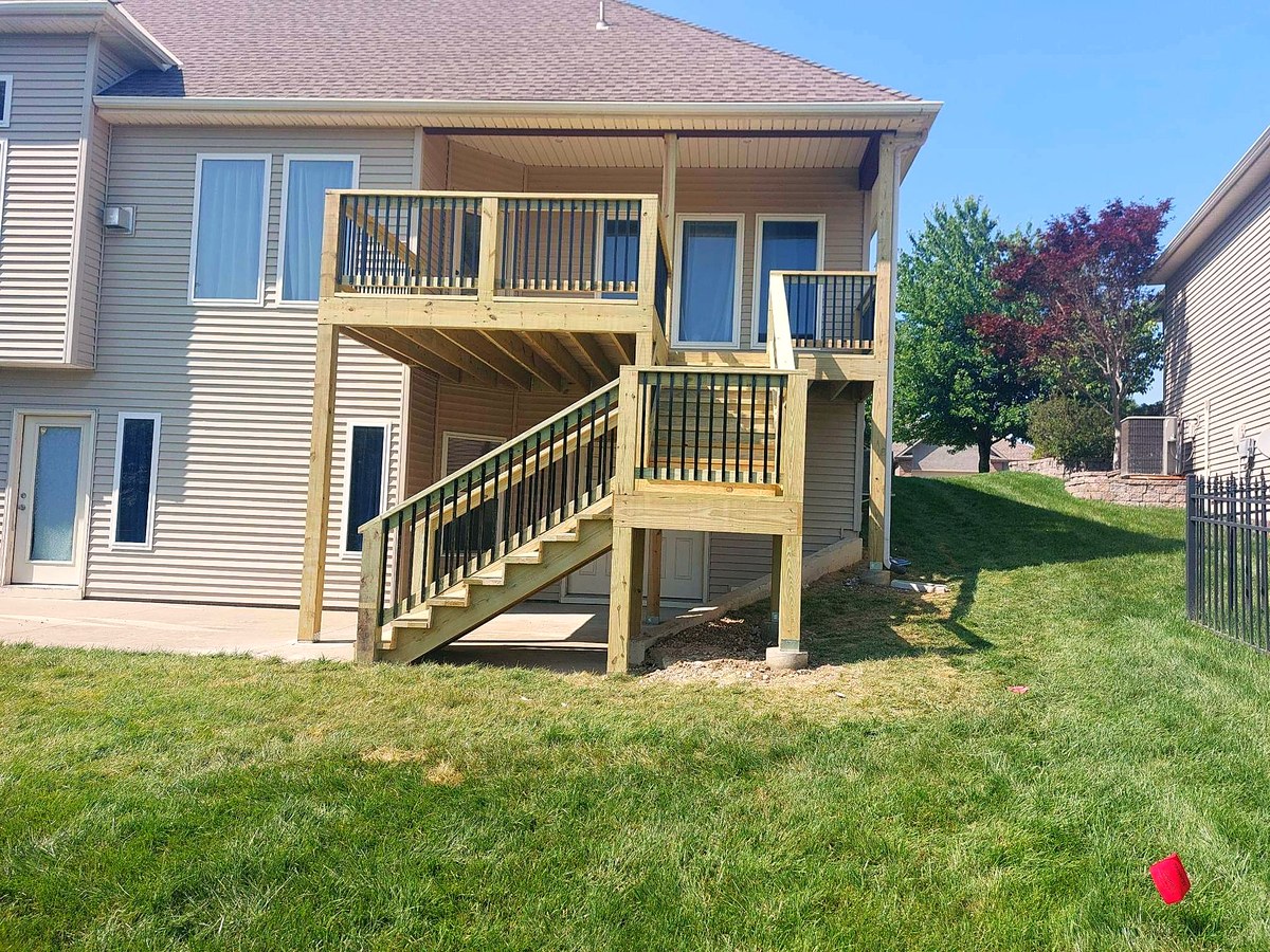 Two-story deck with stairs on the back of a suburban home.